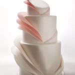 Layered folds in ombréd hues of white, blush and pink surround this pearlescent wedding cake