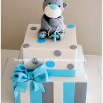 Christening design featuring Tatty Teddy Bear holding rosary beads on a beautifully designed 2 tiered sharp edged square cake